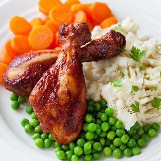 2 roast chicken drumsticksserved with carrots, peas and mash