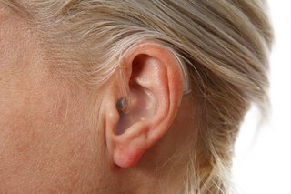 A hearing aid attached behind the ear. A plastic tube connects the device behind the ear to a mould inside the ear.