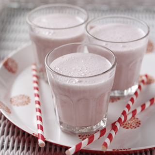 3 glasses on a plate, filled with raspberry and banana shake.
